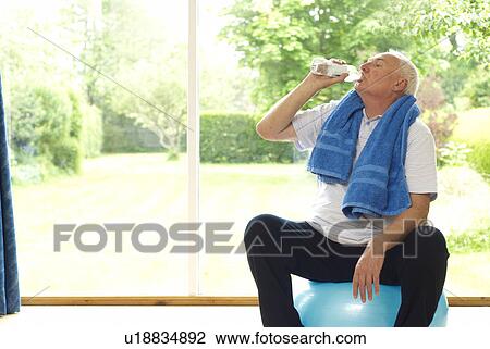 Stock Image - Older man drinking water during exercise. Fotosearch