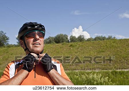 Picture - Older man fastening bike helmet. Fotosearch
