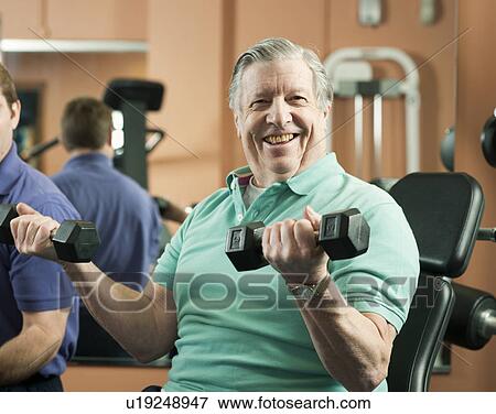 Stock Photo - Older man lifting weights in gym. Fotosearch