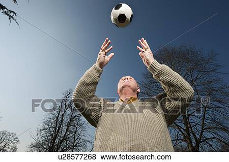 Stock Photo - Older man playing with soccer ball. Fotosearch