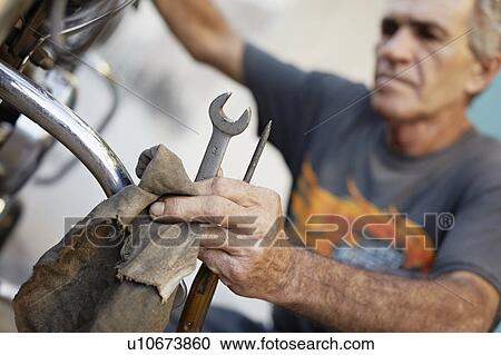 Older man repairing his motorcycle View Large Photo Image Stock Image - Older man repairing his motorcycle. Fotosearch