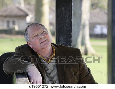 Stock Image - Older man sitting on park bench. Fotosearch