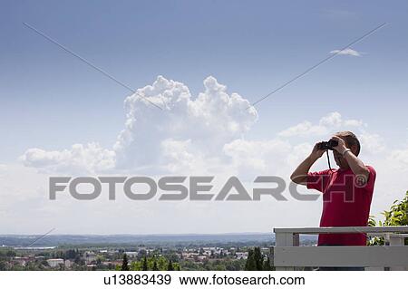 Older man using binoculars on roof View Large Photo Image Stock Photo - Older man using binoculars on roof. Fotosearch