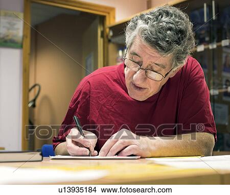 Picture - Older man writing at desk. Fotosearch