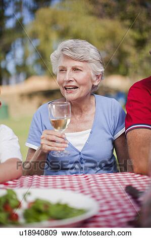 Older woman drinking at picnic table View Large Photo Image Stock Photo - Older woman drinking at picnic table. Fotosearch
