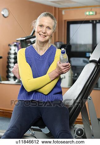 Older woman drinking water in gym View Large Photo Image Stock Image - Older woman drinking water in gym. Fotosearch