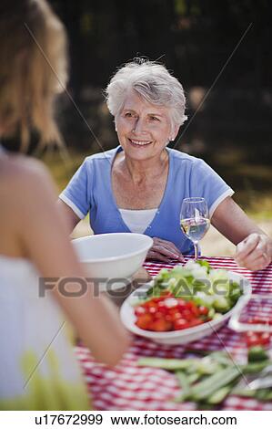 Stock Photo - Older woman sitting at picnic table. Fotosearch