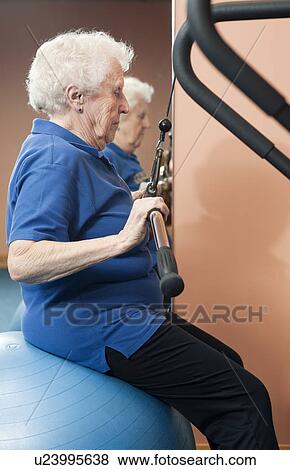 Stock Photo - Older woman using exercise machine. Fotosearch