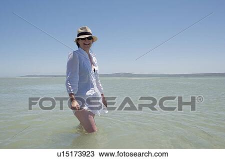 Stock Image - Older woman walking in water. Fotosearch