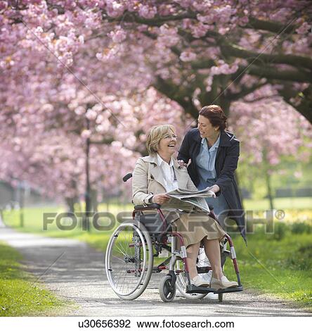 Older woman with caretaker in park View Large Photo Image Stock Image - Older woman with caretaker in park. Fotosearch