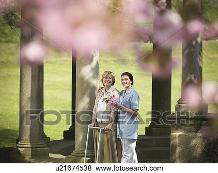 Older woman with caretaker in park View Large Photo Image Stock Photo - Older woman with caretaker in park. Fotosearch