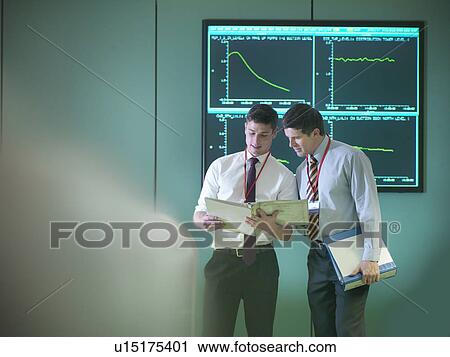 Stock Image - Operators in power station control room. Fotosearch