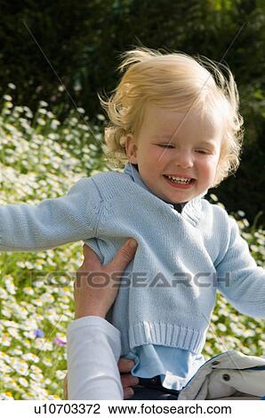 Parent holding baby in field of flowers View Large Photo Image Stock Image - Parent holding baby in field of flowers. Fotosearch
