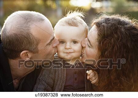 Parents kissing baby’s cheeks outdoors View Large Photo Image Stock Photo - Parents kissing baby’s cheeks outdoors. Fotosearch