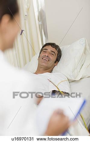 Stock Image - Patient with doctor in hospital bed. Fotosearch