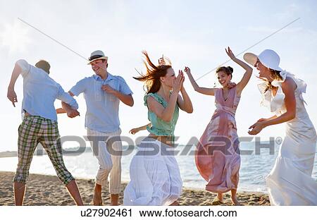Stock Image - People dancing together on beach. Fotosearch