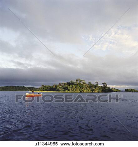 Stock Photography - People fishing from canoe on lake. Fotosearch