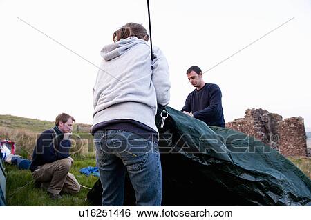 Stock Photograph - People pitching tent at campsite. Fotosearch