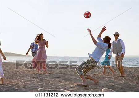 Stock Image - People playing with soccer ball on beach. Fotosearch