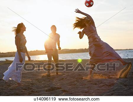 Stock Photo - People playing with soccer ball on beach. Fotosearch