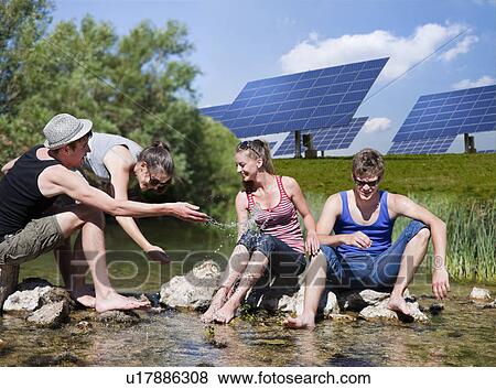 Stock Photo - People sitting in river by solar panels. Fotosearch