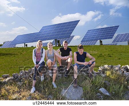 Picture - People sitting on wall by solar panels. Fotosearch
