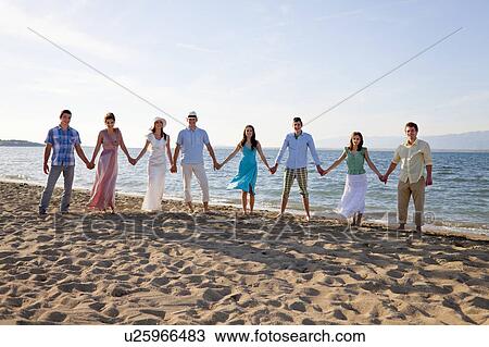 People standing hand-in-hand on beach View Large Photo Image Stock Image - People standing hand-in-hand on beach. Fotosearch