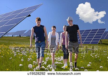 Stock Image - People walking by solar panels. Fotosearch