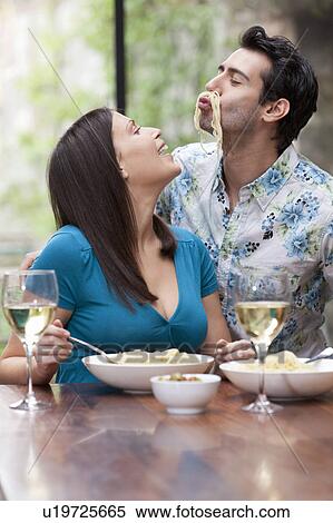 Stock Photography - Playful couple eating together at table. Fotosearch