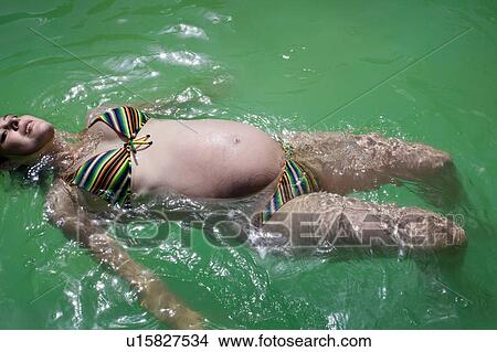 Pregnant woman floating in pool View Large Photo Image Picture - Pregnant woman floating in pool. Fotosearch