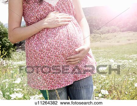 Stock Image - Pregnant woman holding her belly. Fotosearch