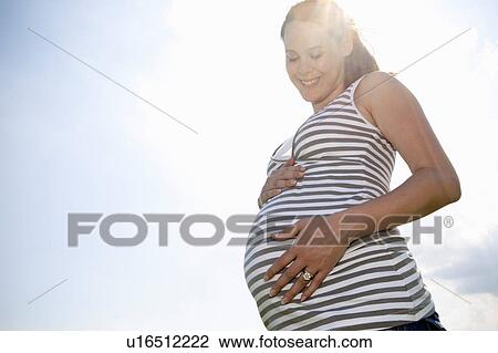 Pregnant woman holding her belly View Large Photo Image Stock Image - Pregnant woman holding her belly. Fotosearch
