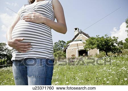 Stock Image - Pregnant woman holding her belly. Fotosearch