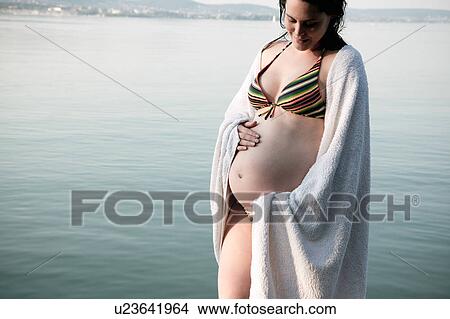 Pregnant woman standing by lake View Large Photo Image Picture - Pregnant woman standing by lake. Fotosearch