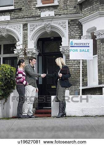 Stock Image - Realtor showing couple property for sale. Fotosearch
