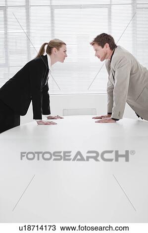 Rival business people leaning over desk View Large Photo Image Stock Image - Rival business people leaning over desk . Fotosearch