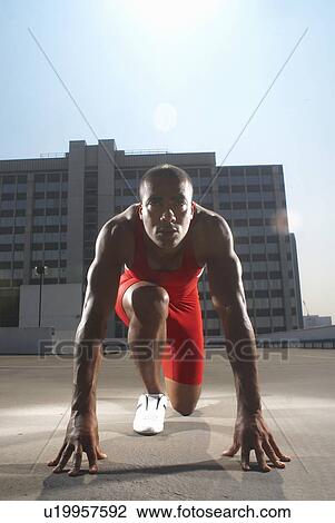 Stock Image - Runner in start position on rooftop. Fotosearch