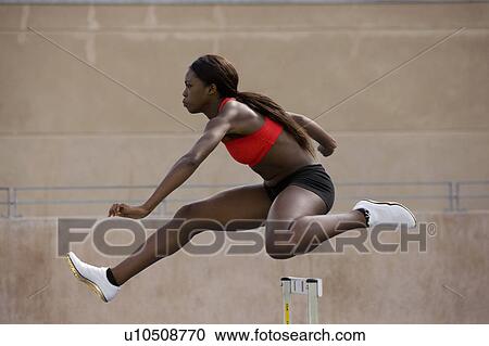 Runner jumping over hurdles on track View Large Photo Image Stock Image - Runner jumping over hurdles on track. Fotosearch
