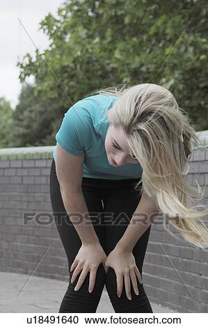 Stock Image - Runner resting on city street. Fotosearch