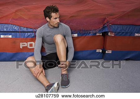 Stock Photo - Runner sitting against mattress. Fotosearch