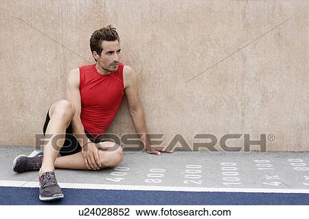 Stock Image - Runner sitting against wall. Fotosearch