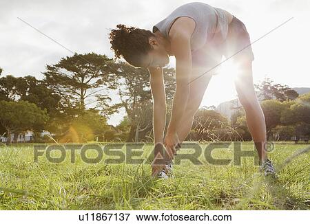 Runner stretching in field View Large Photo Image Stock Photo - Runner stretching in field. Fotosearch