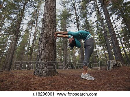 Stock Image - Runner stretching in forest. Fotosearch
