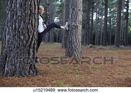 Stock Photo - Runner stretching in forest. Fotosearch