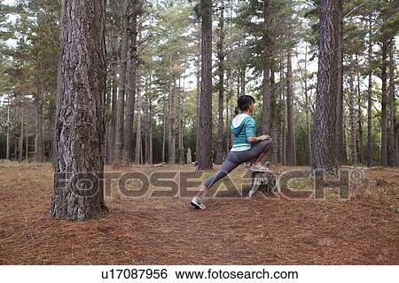 Stock Photograph - Runner stretching in forest. Fotosearch