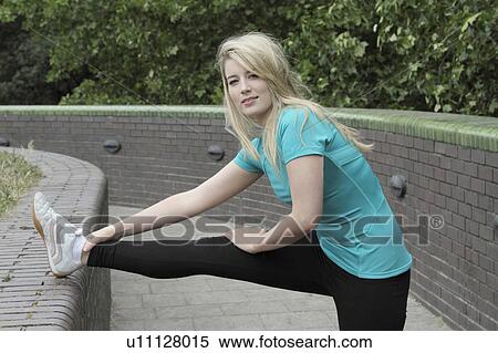 Stock Photography - Runner stretching on brick wall. Fotosearch
