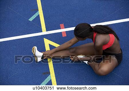 Stock Image - Runner stretching on track. Fotosearch
