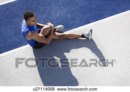 Stock Photo - Runner stretching on track. Fotosearch