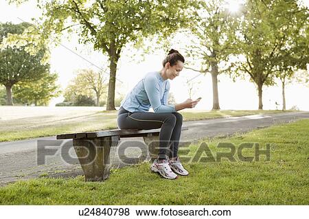 Stock Photo - Runner using cell phone in park. Fotosearch