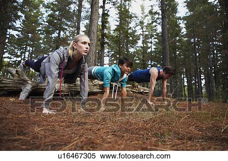 Stock Photography - Runners doing push-ups in forest. Fotosearch